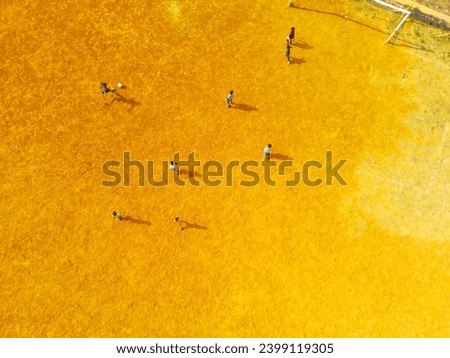 Sports Photography. Aerial Landscapes. Drone view of children running around chasing a ball on the field. Children are playing football in the morning. Aerial Shot from a flying drone.