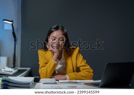 Young Asian business woman uses computing concept with calculator to calculate business principles. Work graph paper placed on table, accounting statistics concept at office.