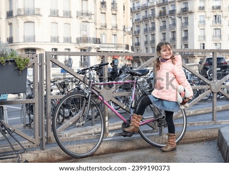 Little girl near a bicycle in European city.