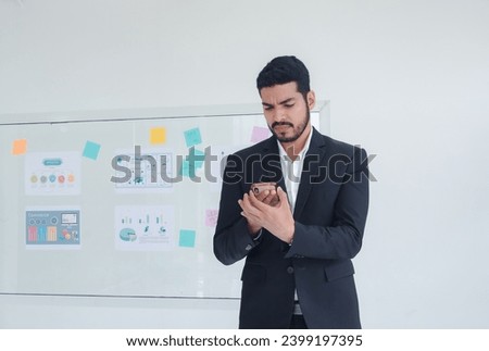 Business man portrait asian one person wearing a black suit handsome standing looking success committed hand holding mobile phone and laptop ready for work inside the office, with white background