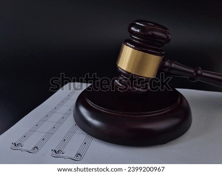 Music copyright. Treble clef with notes on sheet next to hammer on a black background. Music piracy concept