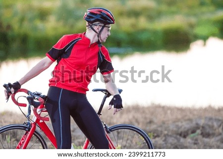 One Male Cyclist Resting Outdoors on His Bike on Nature Background With Professional Outfit. Horizontal Image Composition