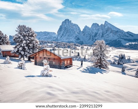 Tourist takes picture on smartphone of Alpe di Siusi village with Plattkofel peak on background. Cold morning view of Dolomite Alps. Snowy outdoor scene of Ityaly, Europe. Traveling concept background