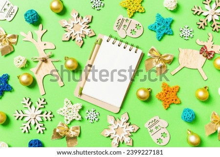 Top view of notebook on green background with New Year toys and decorations. Christmas time concept.