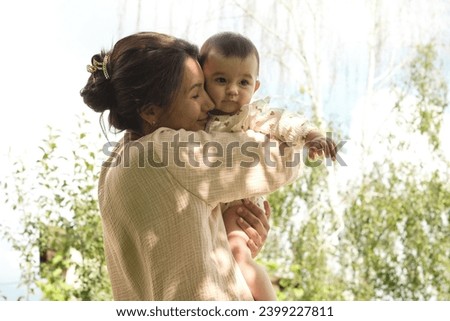 A woman cherishes a moment with a baby outdoors, an embodiment of maternal love. This captures the essence of nurturing in nature's lap. Royalty-Free Stock Photo #2399227811