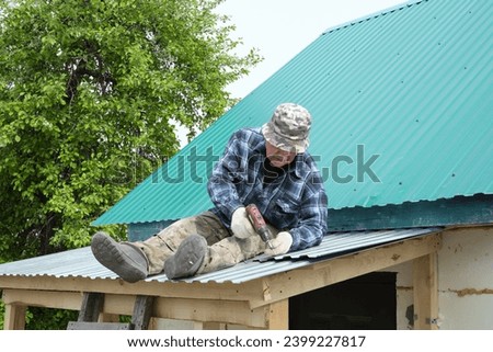 On his roof, this pensioner applies his life-long skills to a DIY project, ensuring his home is well-maintained and weatherproof. Royalty-Free Stock Photo #2399227817