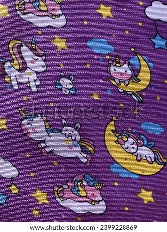 Dinir material with a sleeping unicorn motif on a purple background