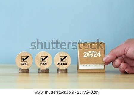 Happy New Year 2024 banner background. 2024 numbers year with target dart icon on desk calendar with hand turns over a calendar sheet.  Goal, Plan, Action on wooden cube. Business goals plan action.
