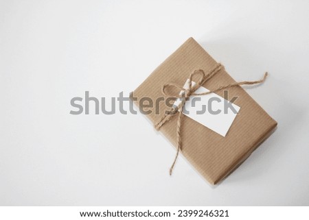 Valentine's Day. Gift Box Wrapped in Brown Kraft Paper, Decorated with Twine Bow and Gift Tag. Holiday Gifts Packaging Design.