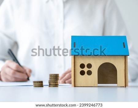 Client signing home loan or real estate purchase agreement. Miniature house and coins on the table. Concept of mortgage and buying and selling property. Selective focus