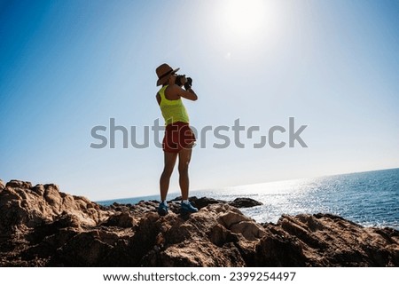 Woman taking photo on sunrise seaside rocky mountains