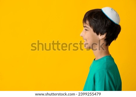 Little Israeli boy in kipa on yellow background
