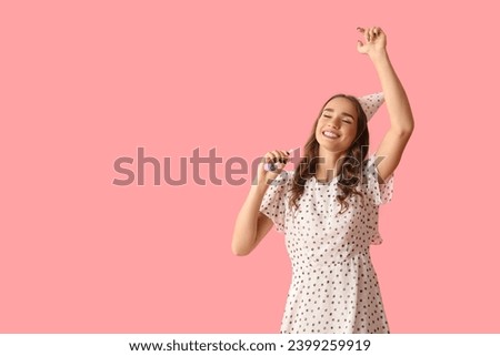 Happy young woman with party whistle celebrating Birthday on pink background