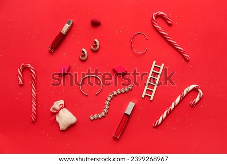 Christmas composition with makeup cosmetics, jewelry and decor on red background