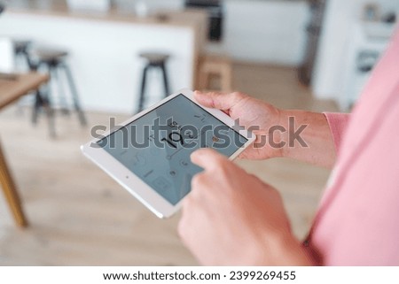 Man using smart thermostat, adjusting, lowering heating temperature at home. Concept of sustainable, efficient, and smart technology in home heating and thermostats. Royalty-Free Stock Photo #2399269455