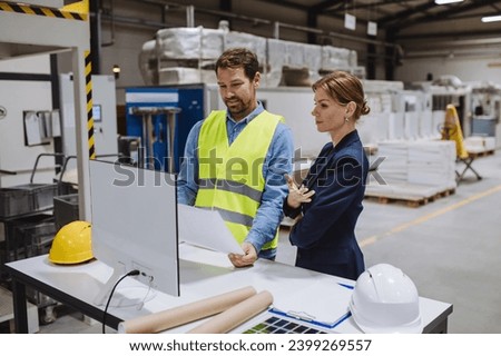 Female engineer reading technical documentation with project manager in modern industrial factory, talking about new production project, investment. Team management in manufacturing facility. Royalty-Free Stock Photo #2399269557