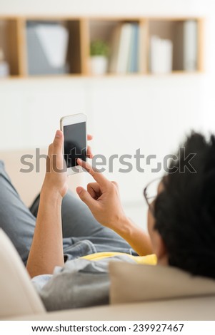 Man lying on the sofa and using his phone, focus on screen