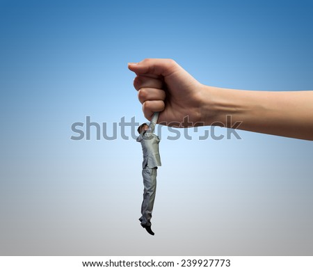 Close up of human hand holding miniature of businessman