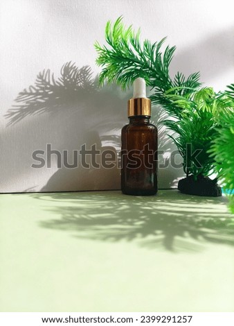 Amber bottle with dropper on a minimalist and exotic green leafy background