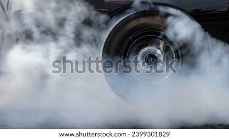 Car burnout wheels tire with white smoke,Car wheel burnout with smoke from the spinning tyre, Drag car wheel burns tires preparation for the race. Royalty-Free Stock Photo #2399301829