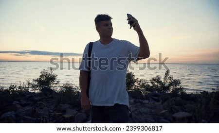 Young man tourist enjoying beautiful sunset, taking photo