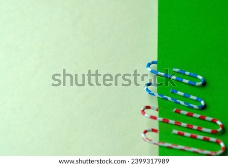 Red and blue paper clips on green blank sheets, stationery art background, close-up