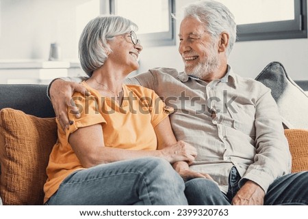 Happy laughing older married couple talking, laughing, standing in home interior together, hugging with love, enjoying close relationships, trust, support, care, feeling joy, tenderness