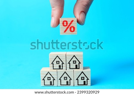Mortgage rate. Woman building pyramid of cubes with percent sign and house icons on light blue background, closeup