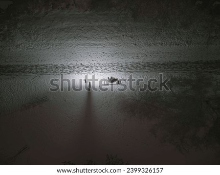 Beautiful landscape with tree, bench and snow at night. Snowy town. Cold weather. Aerial view of winter park. Homeless man siting under street light. Drone view. Stock photo.