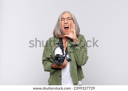middle age woman feeling happy, excited and positive, giving a big shout out with hands next to mouth, calling out. photographer concept