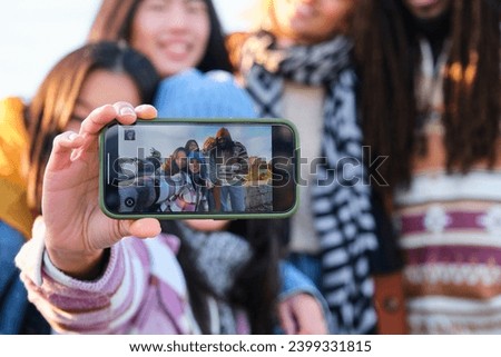 Smartphone screen view of multiracial group of friends taking a selfie at street in autumn.