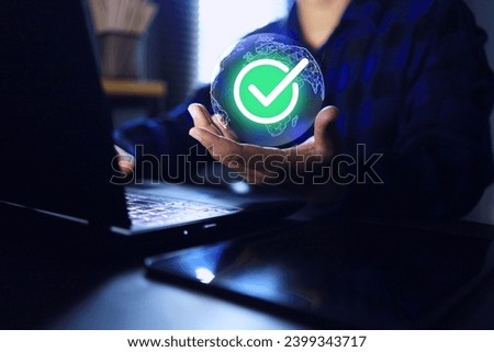 Hand holding globe and correct green checkmark while working on laptop computer screen represent to successful business process via internet or payment is done by online banking