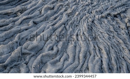 Top view of solidified lava. Dark colored structures from lava flow. Pattern of deferred and broken stones. Different shades of gray. wavy and jagged rigid lava field