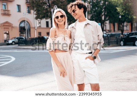 Young smiling beautiful woman and her handsome boyfriend in casual summer clothes. Happy cheerful family. Female having fun. Couple posing in the street background at sunny day. In sunglasses