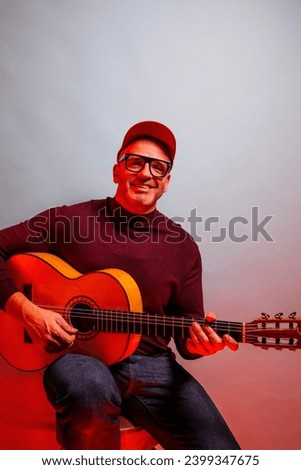 Adult man playing guitar in studio.