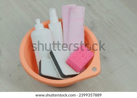 Detergent with washcloths isolated on wooden background. Washing and cleaning in a pink basin. Washcloth for housekeeping. Top view.