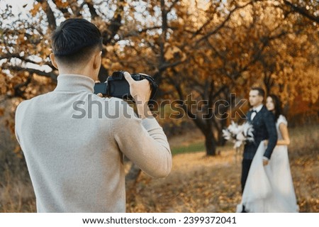 Professional wedding photographer taking pictures of the bride and groom outdoor in autumn