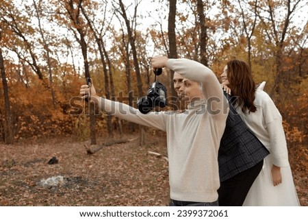 wedding photographer with bride and groom taking selfie with mobile phone in nature