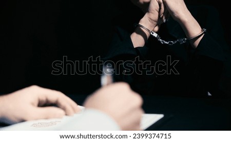 A police officer is writing down information during the interrogation of an arrested woman Royalty-Free Stock Photo #2399374715