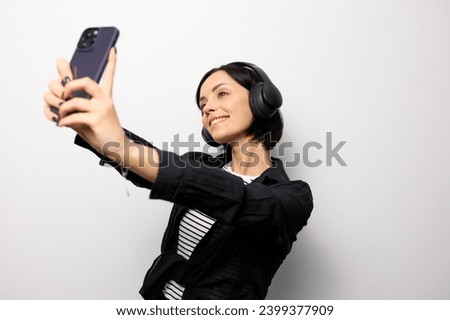 Portrait of a brunette woman with headphones taking a selfie.