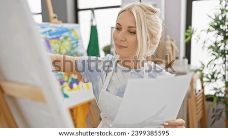 Confident young blonde artist smiling while drawing on paper at the art studio