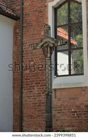 a wooden cross is built against the brick wall of the church