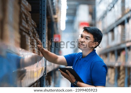 Asian male worker working in warehouse checking product codes between shelves. Logistics business Freight forwarding service