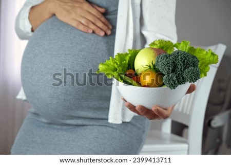 Pregnant woman with bowl of fresh vegetables, broccoli, leaf salad, tomato. Healthy nutrition and diet during pregnancy. Prenatal care, weight control, happy motherhood, new life. Royalty-Free Stock Photo #2399413711