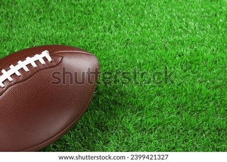 American football ball on green grass, closeup. Space for text