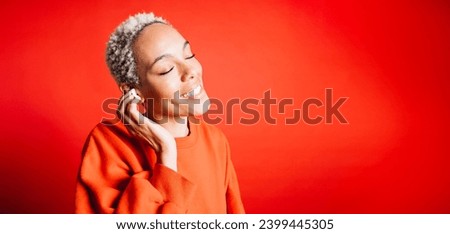 Happy young woman dancing while wearing wireless earphones in a studio. Woman listening her favourite music playlists. Royalty-Free Stock Photo #2399445305