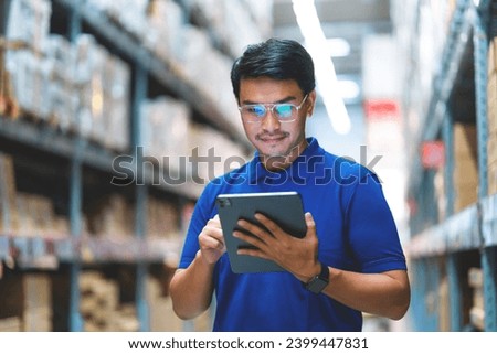 Asian male worker working in warehouse checking product codes between shelves. Logistics business Freight forwarding service