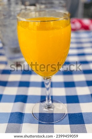 Brunch mimosa orange juice glass drink on blue and white checkered pattern tablecloth with blurred background