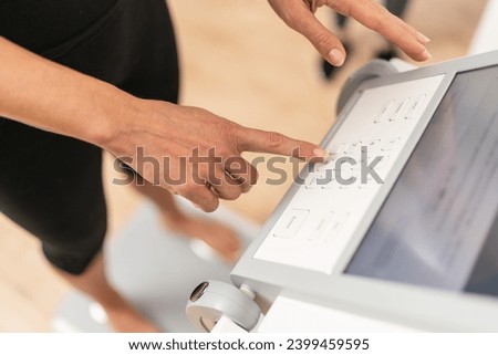 person's hand entering data on a touchscreen interface of a body composition scale during Inbody test in a fitness studio Royalty-Free Stock Photo #2399459595