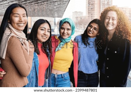 Diverse female friends having fun togehter on city street. Group of multiracial people smiling and hugging on camera Royalty-Free Stock Photo #2399487801